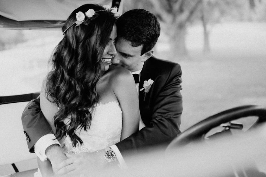 bride and groom embrace in golf cart in black and white